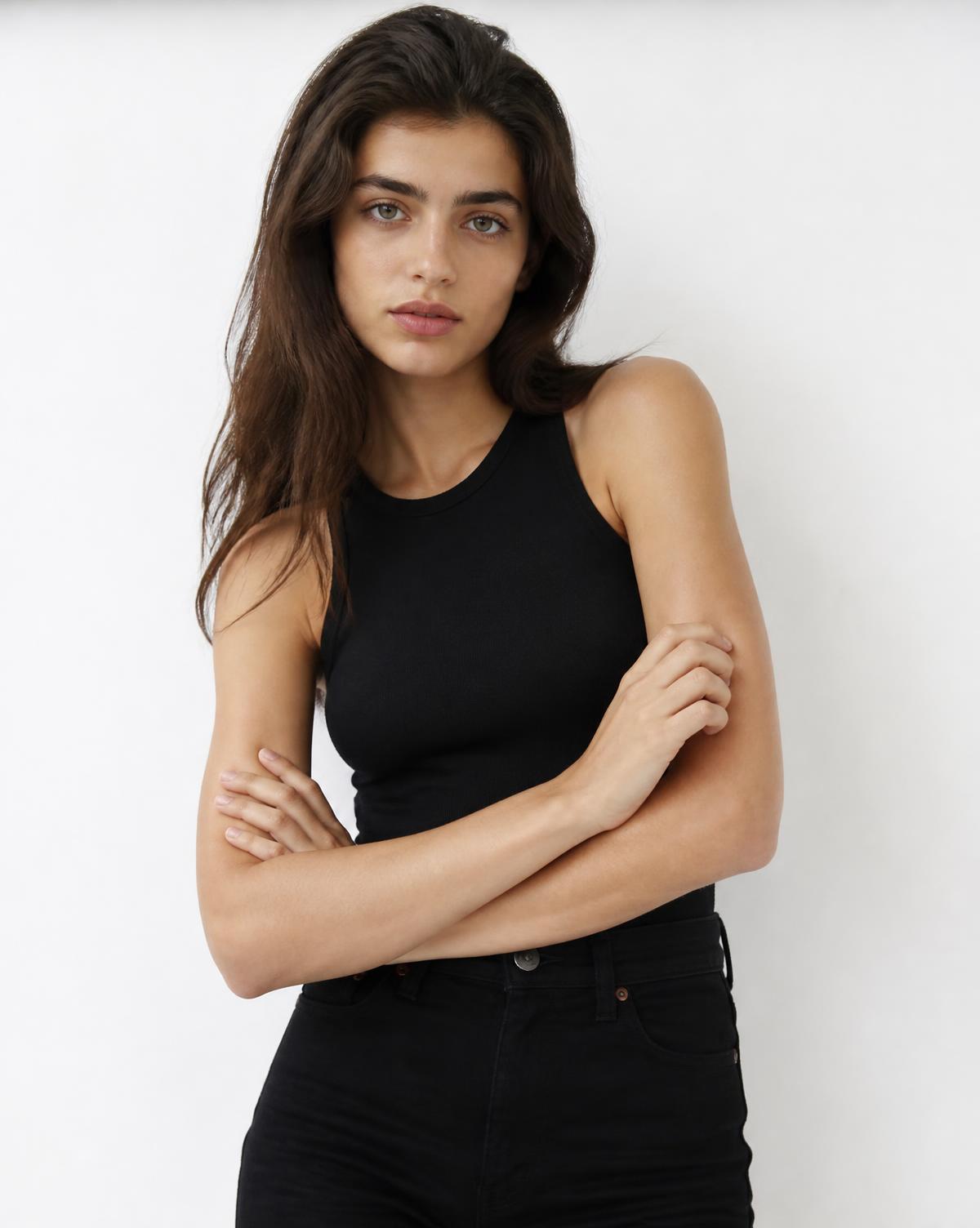 Studio portrait of a model in simple black clothing against a white backdrop